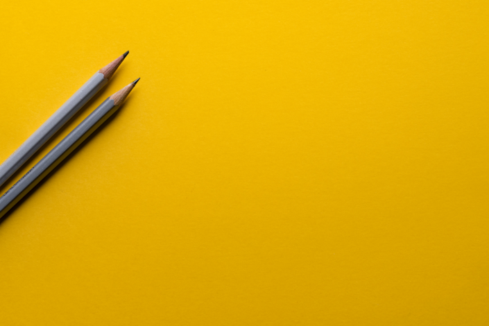2 Bleistifte liegen auf einem gelben Blatt Papier
